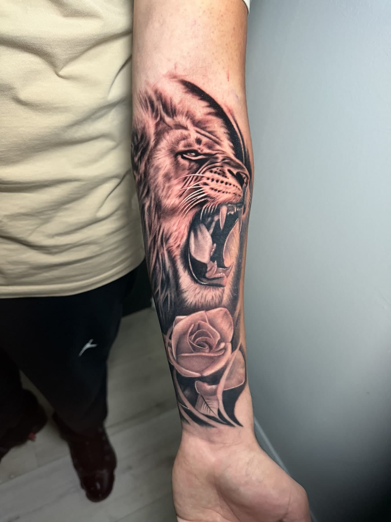 Roaring lion and rose forearm — black & gray realism